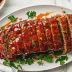 Perfect oven baked meatloaf recipe sliced and ready to serve on elegant platter